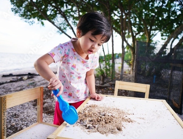 Obraz girl are playing in the sand on a table against the backdrop of the beach