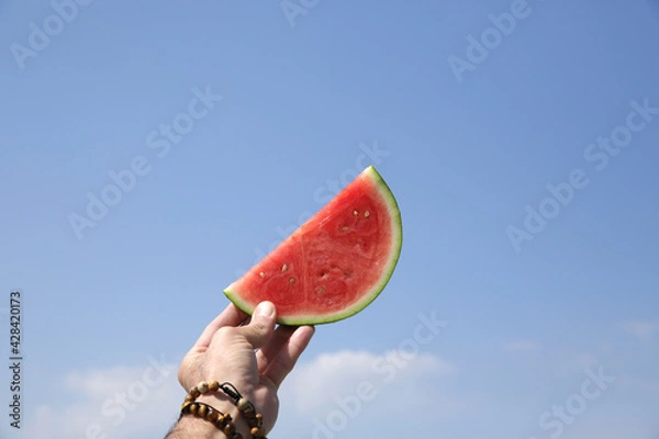Fototapeta juicy slice of watermelon on blue sky background with copy space for text. summer fruit