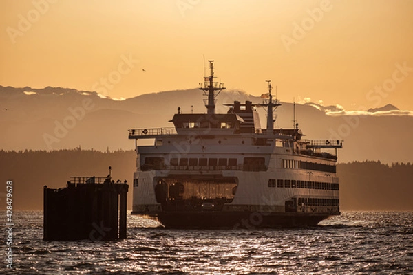Fototapeta A ferry boat comes in to dock during the last hours of sunset