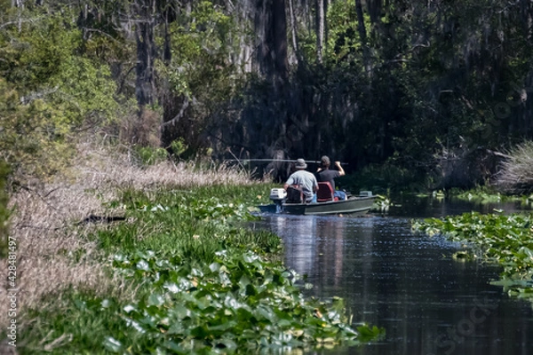 Fototapeta Two men in a flat bottomed Jon Boat fishing a narrow channel in the Okefenokee Swamp in the state of Georgia, USA