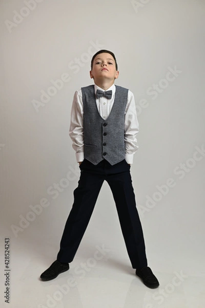 Fototapeta Portrait of a boy in a suit with a bow tie on a white background in full growth