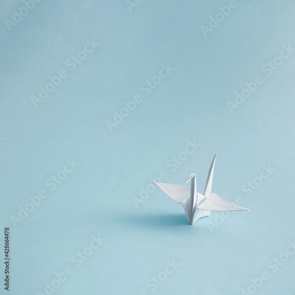 Obraz Minimalistic composition of a white origami crane. Orizuru on pastel blue background.