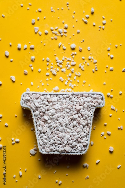 Fototapeta Perlite in a pot-shaped container on a yellow background, vertical image with copy space. Soil amendment and substrates for horticultural use concept.