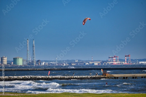 Obraz 強風でウインドサーフィンとカイトサーフィンが走っている海岸の風景