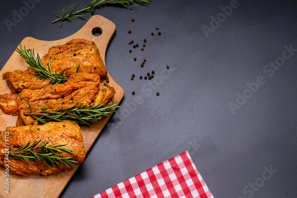 Obraz Raw marinated meat, steaks with rosemary and pepper on a black background
