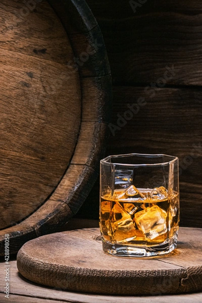 Fototapeta Whiskey in glass with ice is a strong alcoholic drink from an oak barrel. You need to drink whiskey with ice then the whiskey tastes better of an oak barrel.