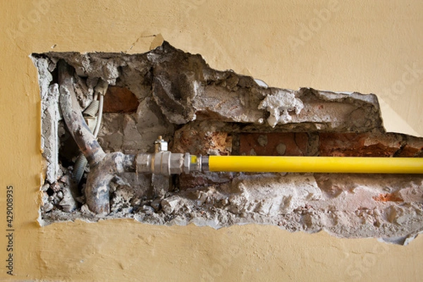 Fototapeta Baustelle mit neuer Rohrleitung in Mauer. 
Aufgestemmte Mauer. Trockenbau.
Construction site with new pipeline in brick wall. 
Pry open wall. Drywall.