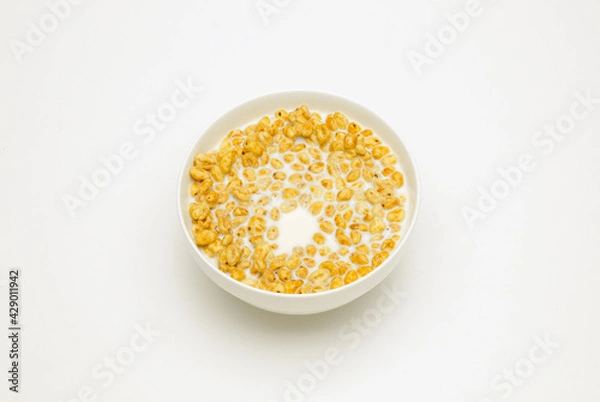 Fototapeta wheat flakes with milk in a white cup on a white background