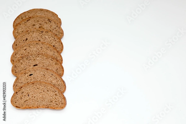 Fototapeta pieces of grey rye healthy bread, laid out in a row as a frame on the left on a white background