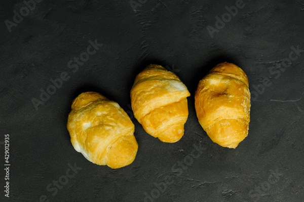 Fototapeta three fresh croissants on a black background