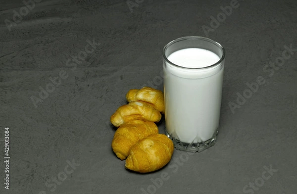 Fototapeta milk in a clear glass and four croissants on a gray background
