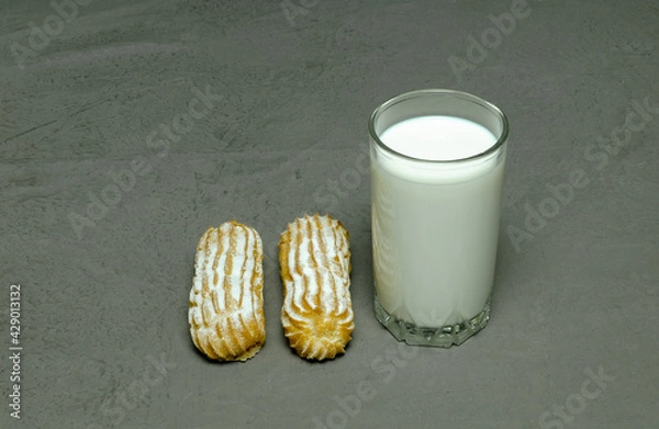 Fototapeta clear glass with milk and two brewed cakes on a gray background