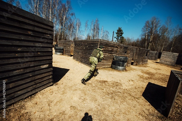 Fototapeta a laser tag game on the training ground. military tactical training with laser weapons. players in military uniforms run around the training ground playing war