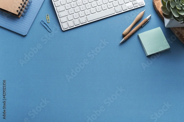 Obraz Blue desk with keyboard blank note, supplies. Stylish home office workspace. Overhead view.