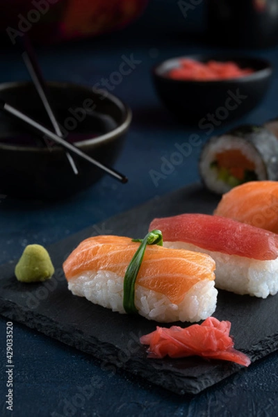 Obraz Rainbow Sushi Roll and nigiri with salmon, tuna, avocado and vegetables placed on black rock.Japan restaurant menu.Japanese food.