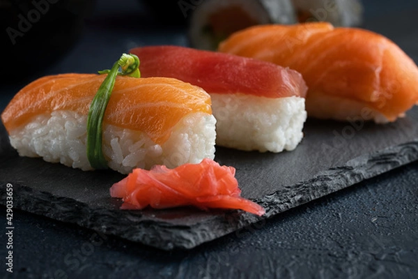 Obraz Rainbow Sushi nigiri with salmon, tuna and vegetables placed on black rock.Japan restaurant menu.Close up.