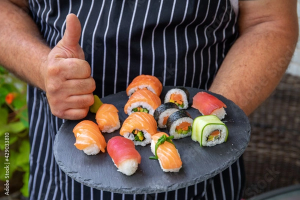 Obraz Closeup of master chef holding food tray with sushi pieces. Concept of food preparation, ready for product placement.Japan restaurant menu.