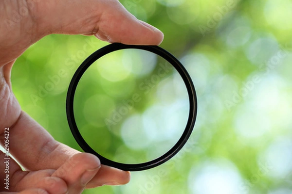 Obraz Hand hold  safety filter  for the lens against blue sky. Light background