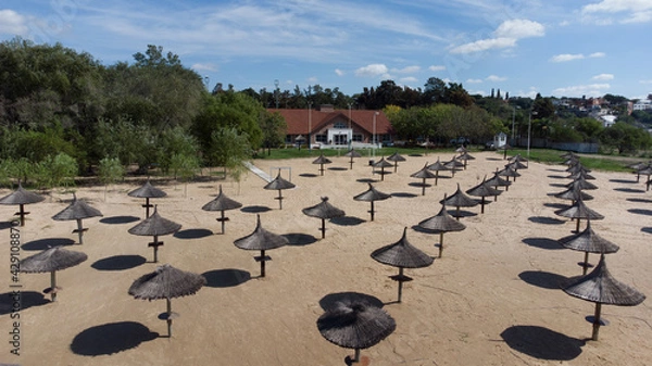 Fototapeta Straw umbrellas on the beach on a sunny day. The concept of rest and relaxation.