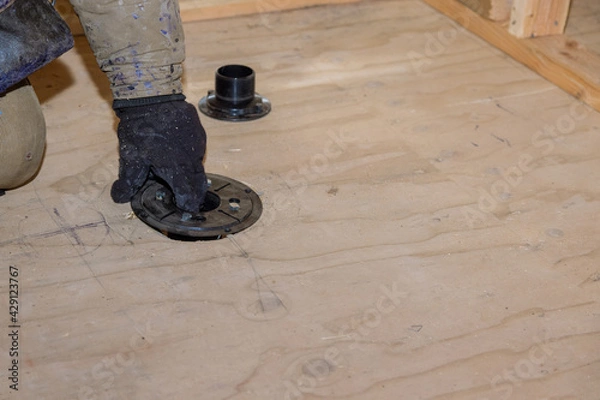 Fototapeta Plumber jointing installing sewage shower drain pipes on a house under construction