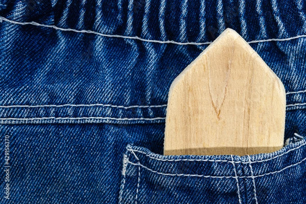 Fototapeta Homemade wooden house toy in the pocket of blue jeans. The concept of eco-friendly toys, the concept of buying a house, a house in your pocket.