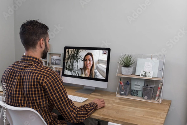 Obraz man makes a video call with a woman, dark-haired man with a beard and plaid shirt makes a video call with a woman from the computer