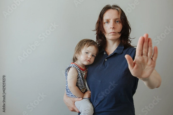 Fototapeta mother and daughter, a child after vaccination. The woman makes a stop gesture. Stop viruses concept
