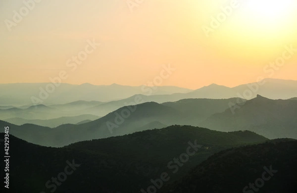 Fototapeta Sunset in the mountains. Layered mountains. Haze at sunset.
