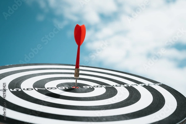 Fototapeta Throw darts on the red target. Is to run a successful marketing business as planned The goal is to go forward. Challenges in running a Dartboard, a target goal, ideas, strategies, marketing, teamwork.