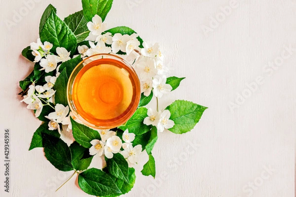 Fototapeta Glass Cup of green Jasmine fragrant, medicinal tea. Alternative medicine. White wooden background. The view from the top. Copy space.