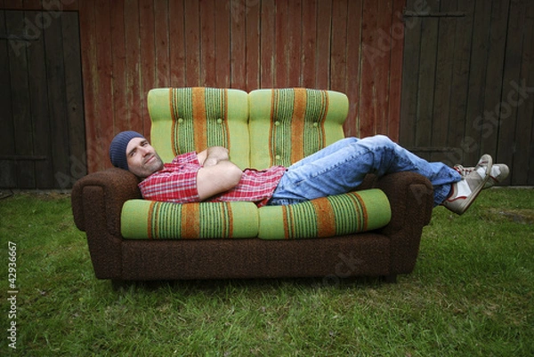 Obraz Lächelnder Mann liegt auf einer Couch