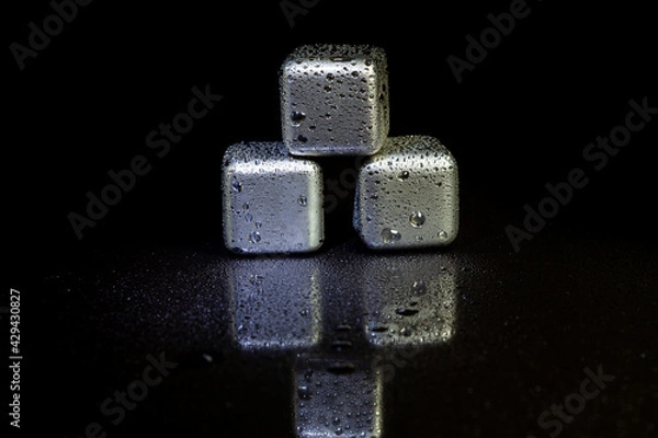 Obraz Stainless steel cubes simulating ice for cooling drinks on a black surface with a reflection.