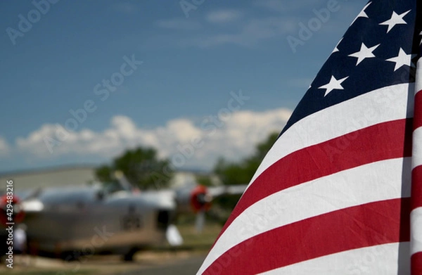 Fototapeta American flag waving to the wind with old airplane in the background
