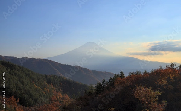 Obraz Panoramic view of Mount Fuji from behind a few forested mountains in the late afternoon on a sunny day