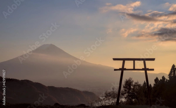 Obraz Late afternoon view of a torii gate and Mount Fuji under a partly-cloudy blue and yellow sunset sky