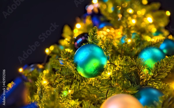 Obraz Night view of a spherical blue Christmas ornament on a Christmas tree illuminated by yellow lights
