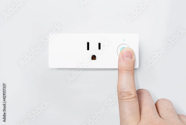 Fototapeta Hand pressing on-off button with blue light active for safety testing electric system on modern smart plug and wifi outlet. Minimal design of electricity with control switch for save energy on a wall.