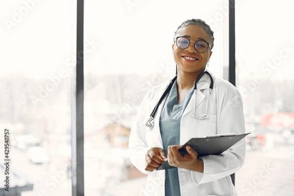 Obraz African doctor standing by window with a folder