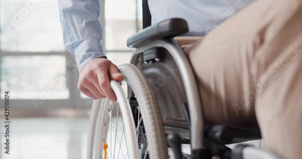 Fototapeta Close up of disabled man riding in wheelchair