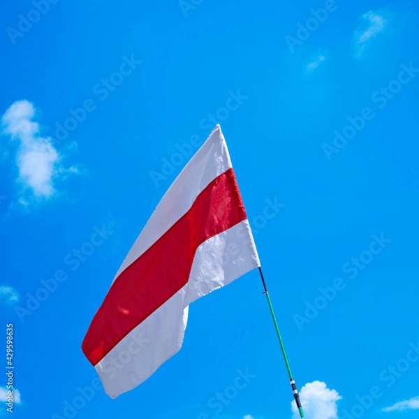 Fototapeta 
Isolated waving Belarusian national flag on blue sky background with clouds . White-red-white flag. A symbol of peaceful protests in Belarus against the dictatorship after presidential elections.
