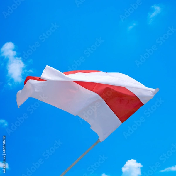 Fototapeta 
Isolated waving Belarusian national flag on blue sky background with clouds . White-red-white flag. A symbol of peaceful protests in Belarus against the dictatorship after presidential elections.