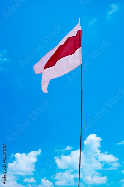 Obraz 
Isolated waving Belarusian national flag on blue sky background with clouds . White-red-white flag. A symbol of peaceful protests in Belarus against the dictatorship after presidential elections.