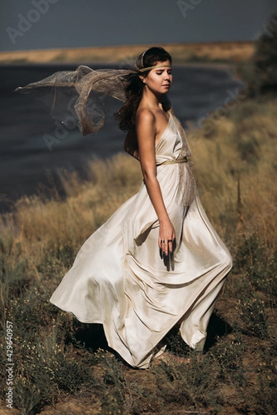 Obraz A beautiful girl in a stilted suit stands on a mountain above the sea, a lake on a sunny day.