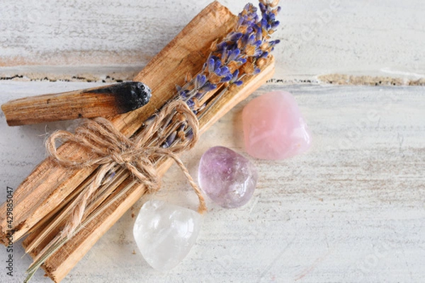 Fototapeta A close up image of holy wood incense sticks with healing rose quartz and amethyst crystals. 