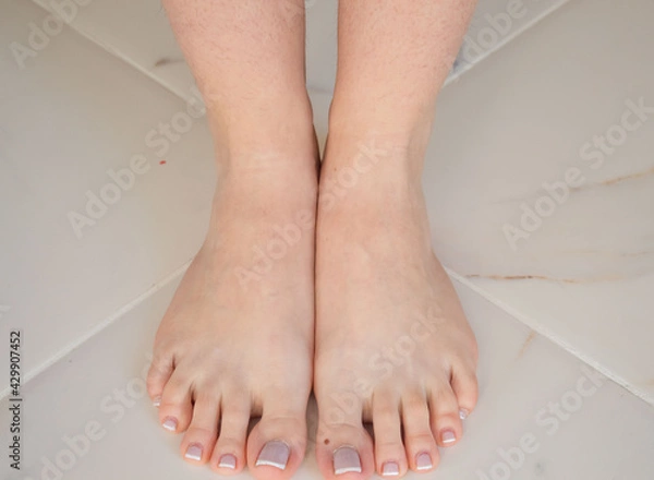 Fototapeta French pedicure on beautiful well-groomed female legs. Large manicure on white background done quality in a salty spa. Spa treatment