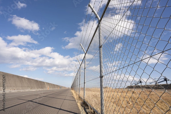 Obraz 一直線に建てられた有刺鉄線付きフェンス