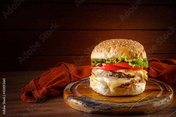 Fototapeta Delicious hamburger on wooden table with rustic wooden background - front view.