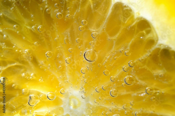 Fototapeta a slice of orange covered with bubbles lies in a glass of sparkling water. Close-up.