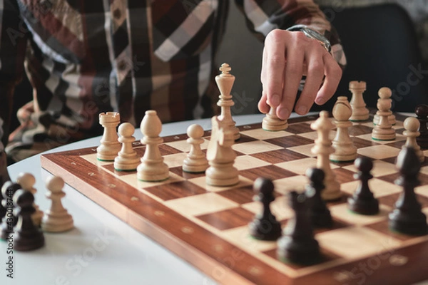 Fototapeta game of chess a game of chess the player making a move by a chess fish. Chess board from wood