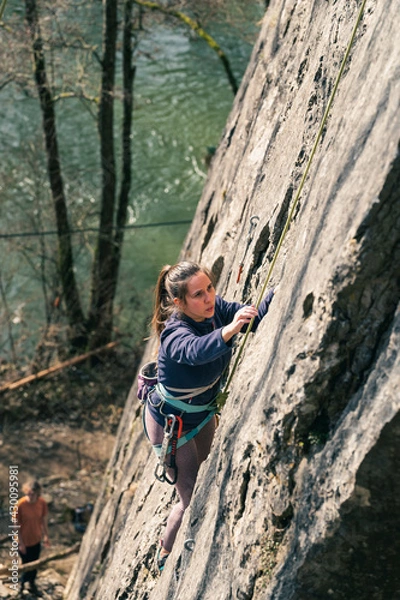 Obraz Young female climber concentrates on her next move on the climbing route.
